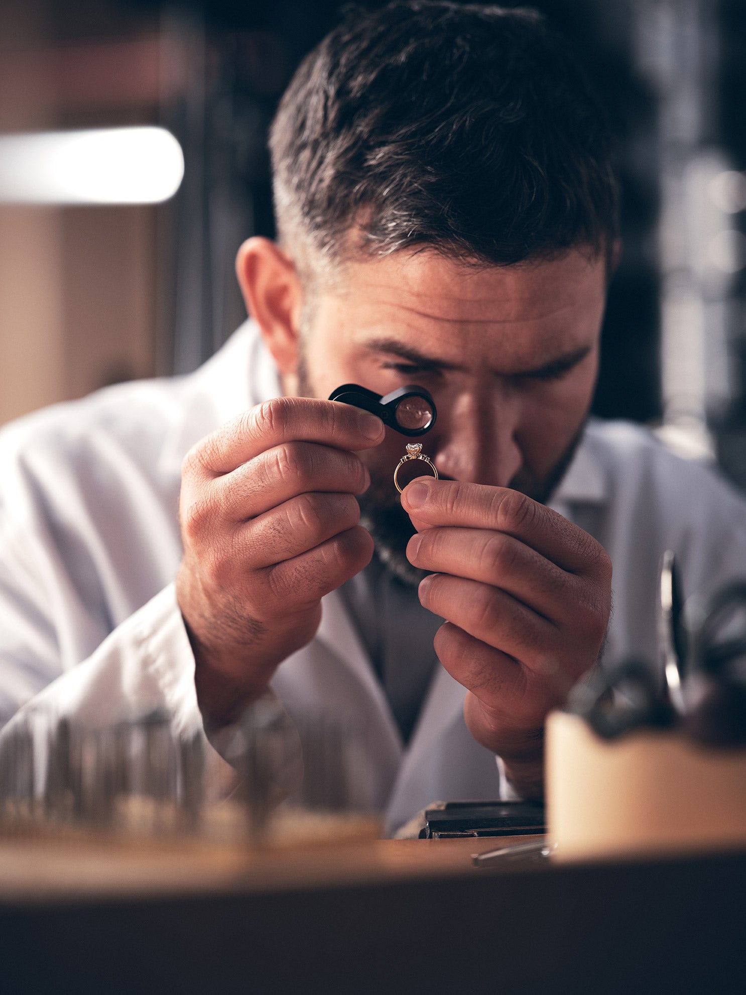 Jeweler inspecting a ring with a loupe in a workshop setting