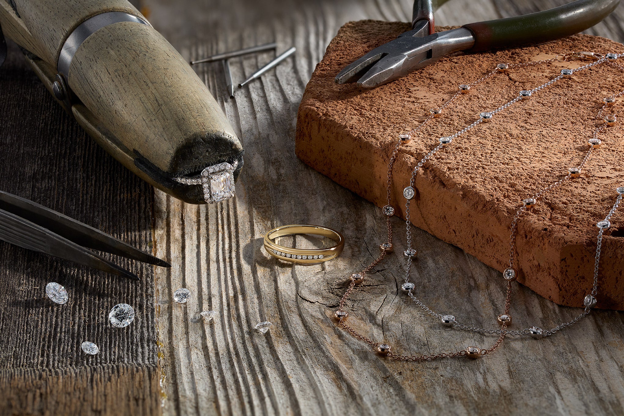 Gold ring, necklace, and tools on a wooden surface