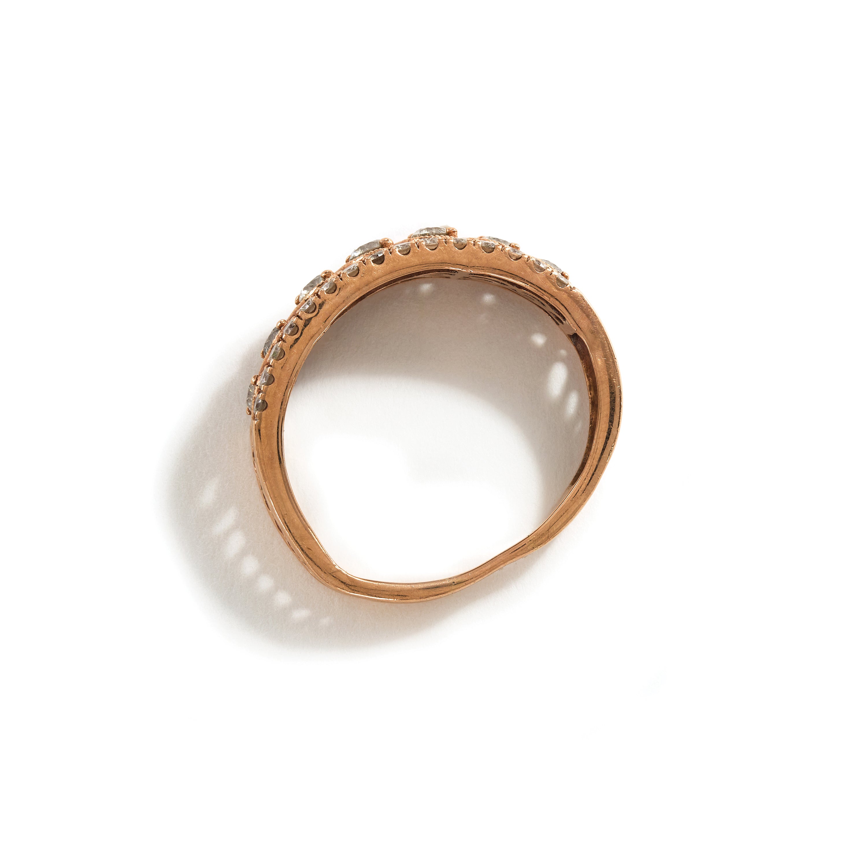 Misshapen rose gold ring with diamonds on a white background