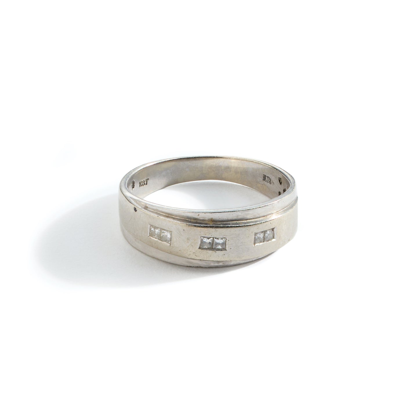 Tarnished white gold and diamond ring in need of polishing on a white background.