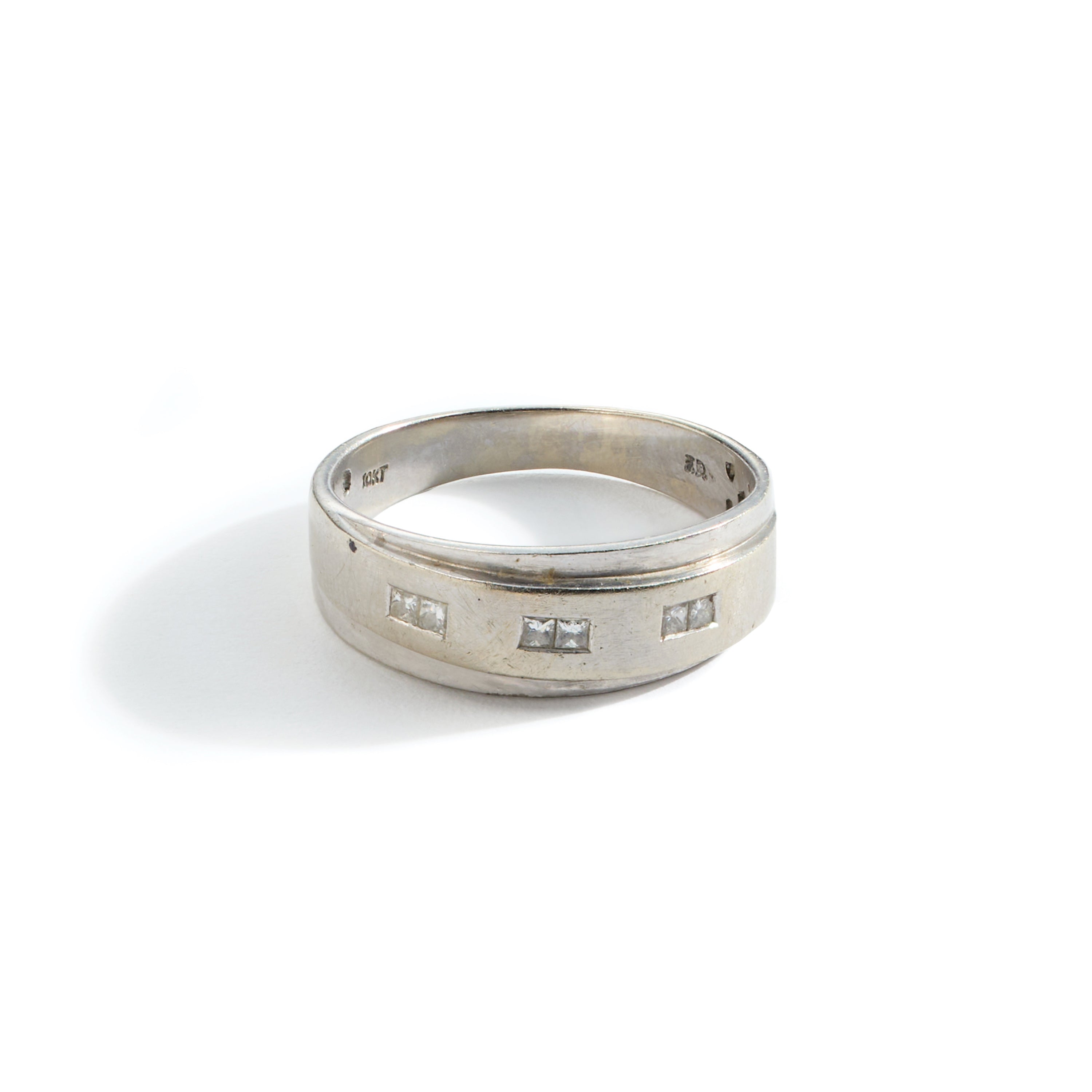 Tarnished white gold and diamond ring in need of polishing on a white background.