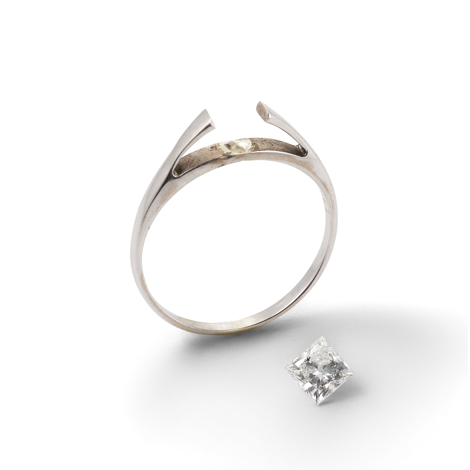 Tarnished white gold ring with broken setting and a loose diamond shown on the side