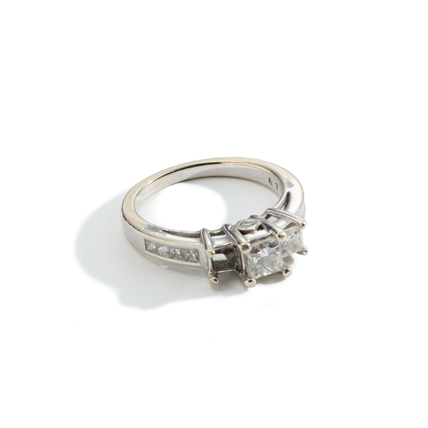 A tarnished three stone white gold engagement ring missing a stone