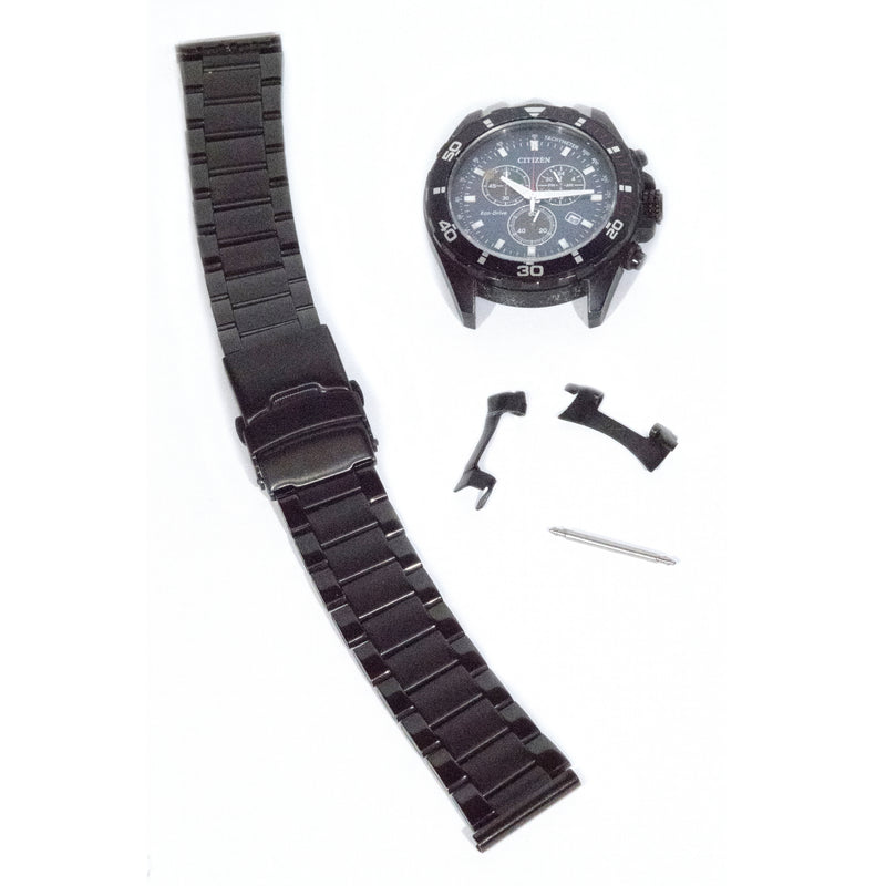 Black watch with face broken apart from band, with loose parts shown to the side on a white background.