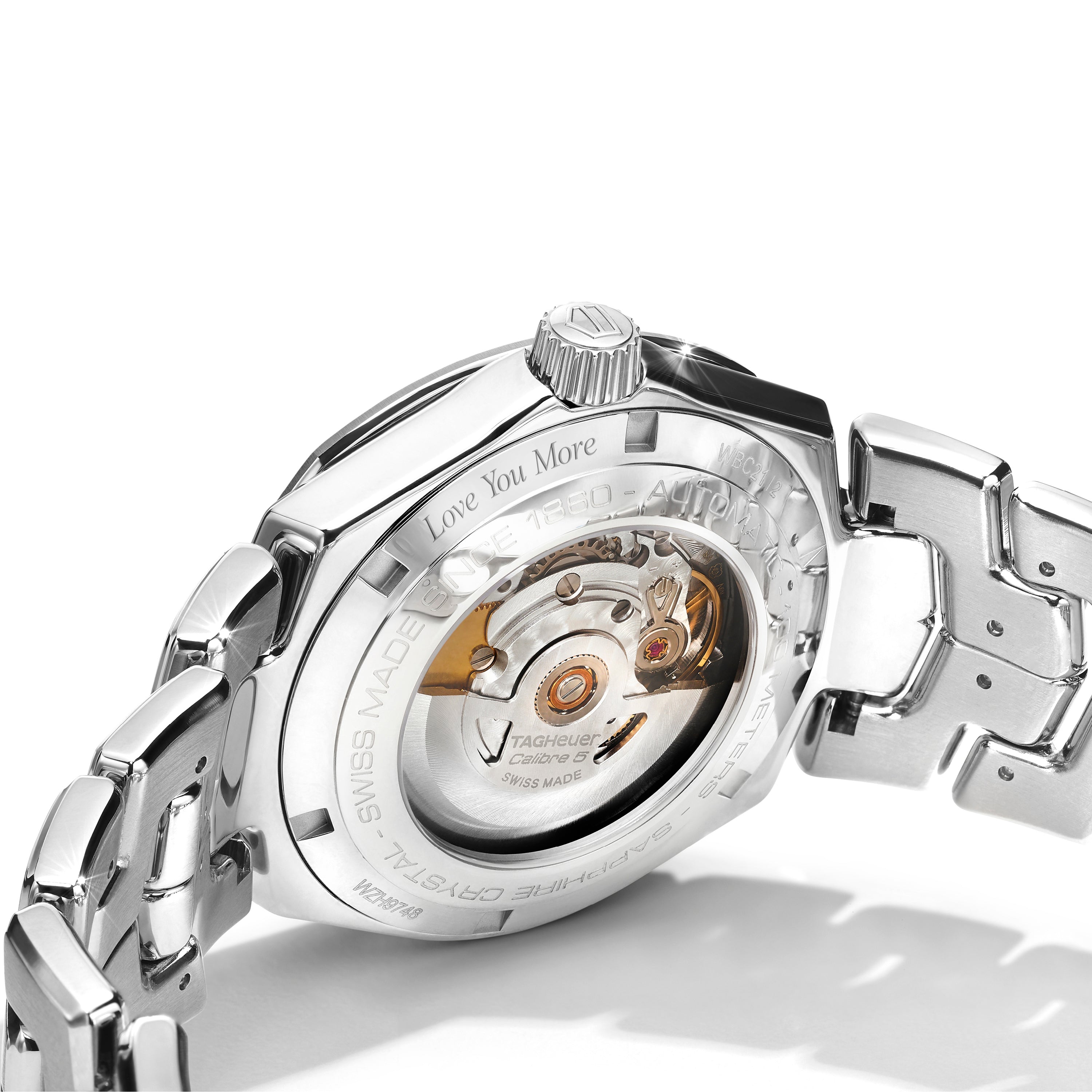 Close-up of a silver watch with an engraving and visible mechanical components shown displayed on a white background